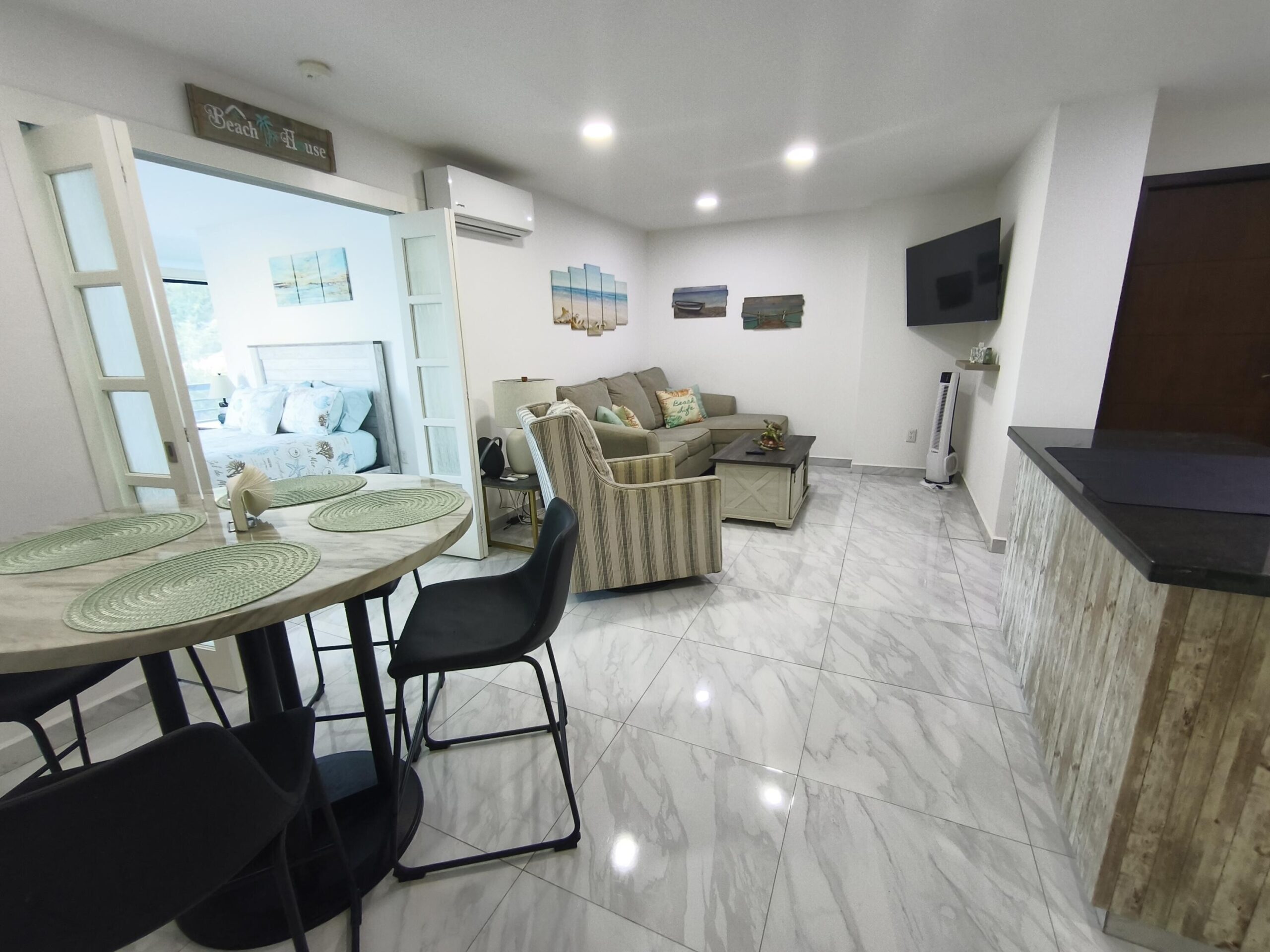 Los Cabos Morgan Residences Morgan Residences Condo 306 offers 67 m² of functional living space with one bedroom, one and a half baths, and a private balcony overlooking the city. The open floor plan connects the kitchen, dining, and living areas with marble-style tile throughout. The kitchen has granite counters, white cabinets, and an island with seating. The bedroom includes an ensuite bathroom with a walk-in shower and opens to the terrace. A separate half bath includes in-unit laundry. The building features a rooftop pool, gym, BBQ area, and for sale